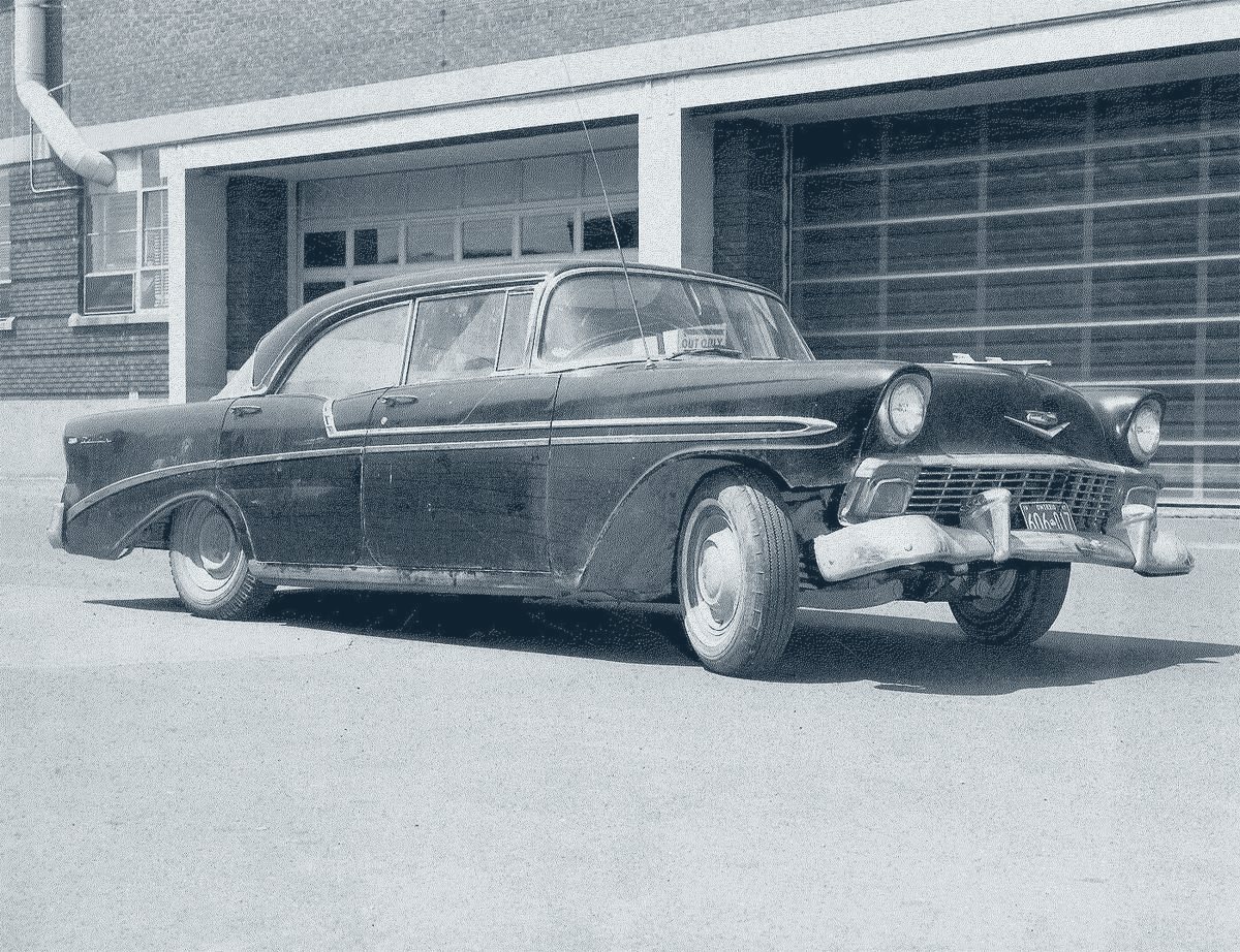 Billy Hall’s black 1956 Chevrolet Bel Air sedan, parked in front of a garage